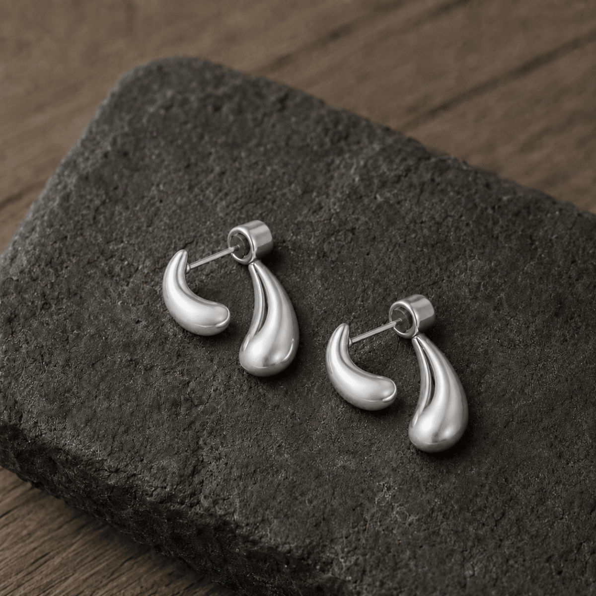 Double Drop Tropfen-Ohrstecker aus Edelstahl in Silber auf dunklem Schiefer