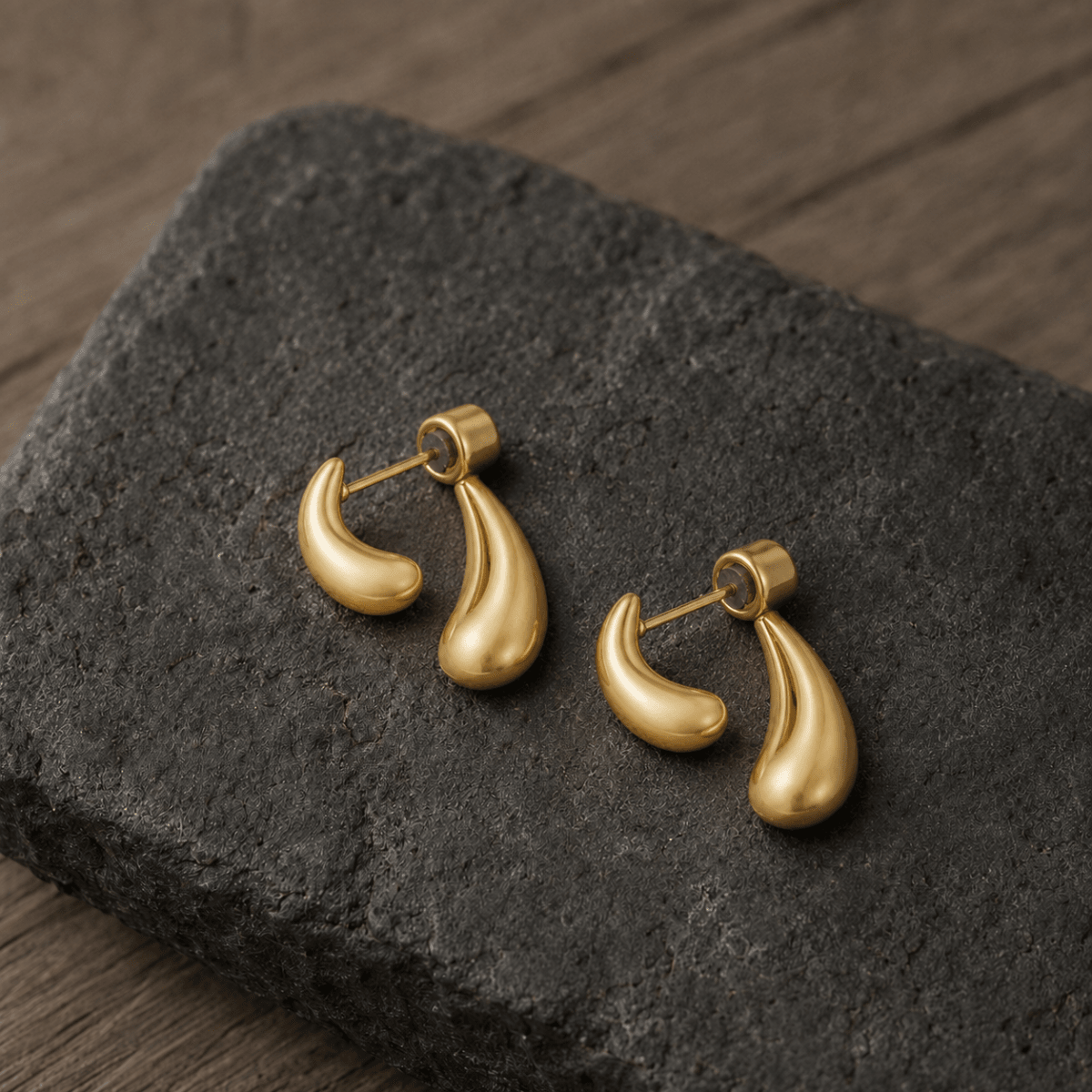 Double Drop Tropfen-Ohrstecker aus Edelstahl in Gold auf dunklem Schiefer